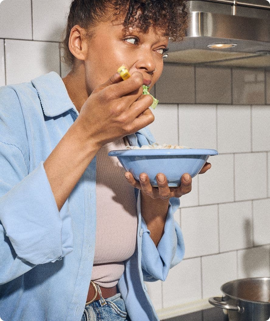 En kvinne med en blå bolle som spiser frokost i kjøkkenet.